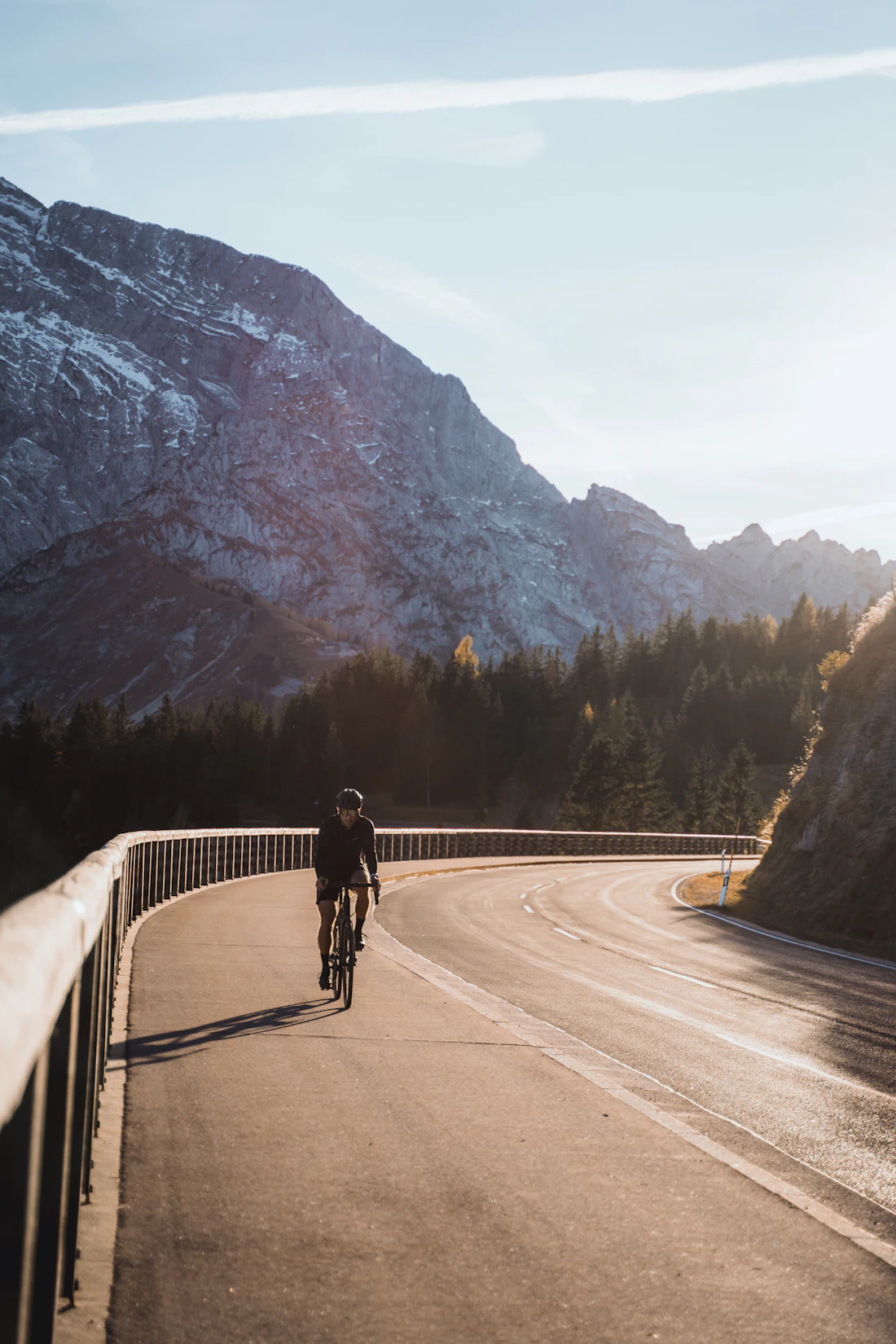 Ein Rennradfahrer auf einer kurvigen Bergstraße im warmen Licht